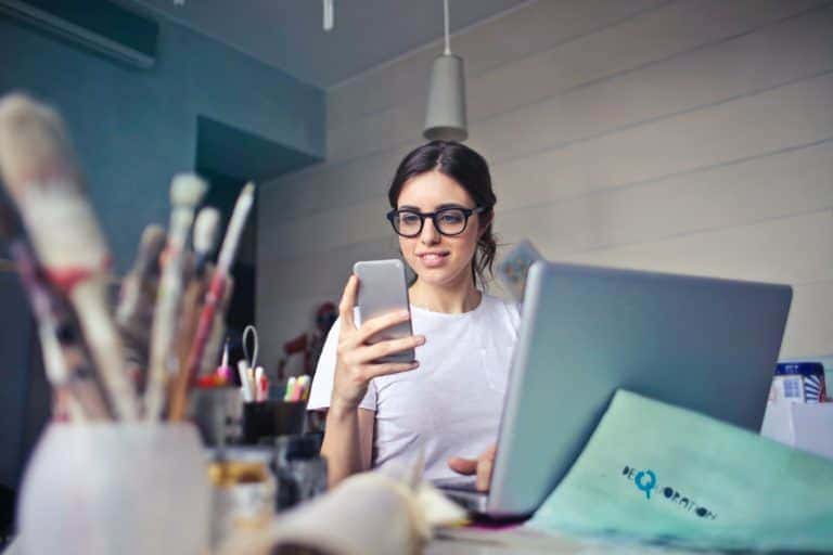 Image of a woman looking at her phone and laptop Image of a woman looking at her phone and laptop